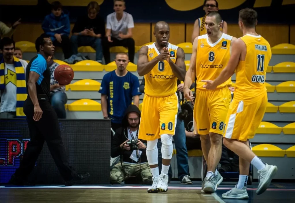 Basketball players of Arka Gdynia at the court's edge, ready for tip-off.