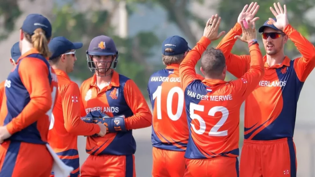Dutch cricket players in their iconic orange jerseys, pre-match huddle.