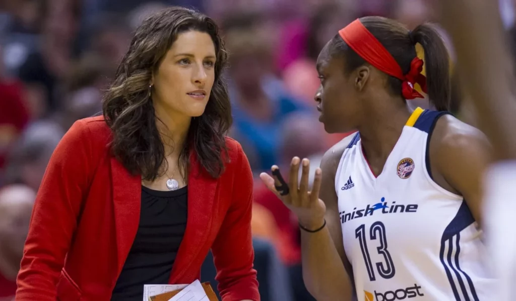 Stephanie White in conversation with a player on the court.