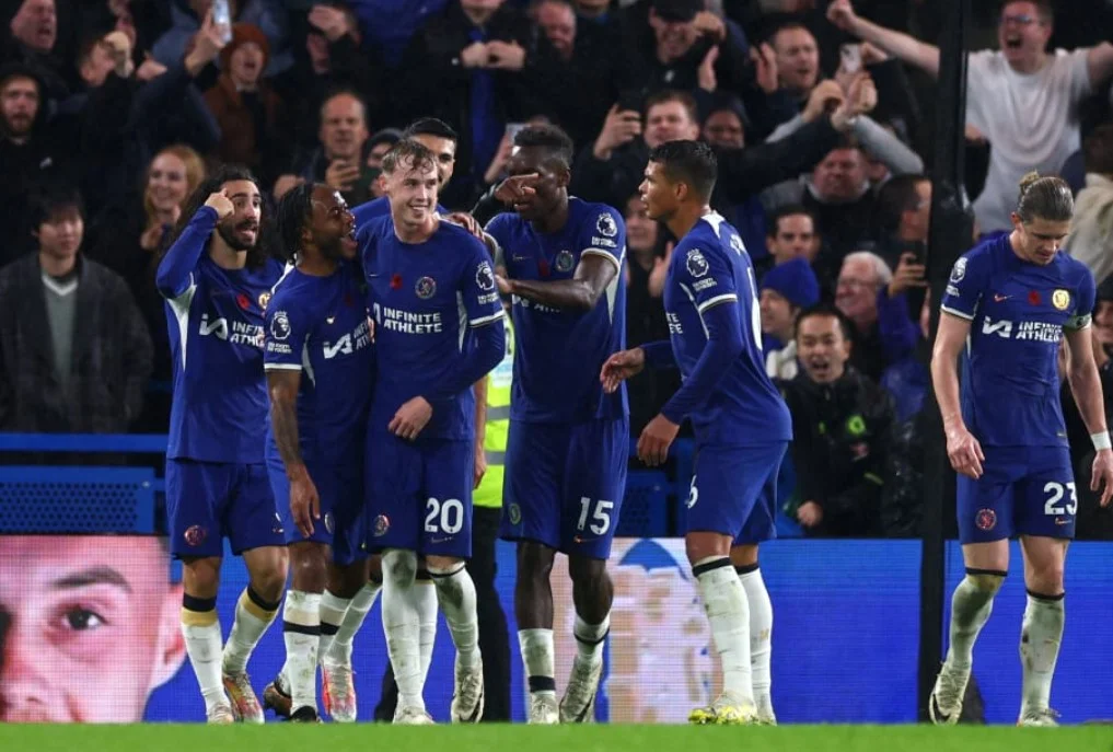 Chelsea footballers embracing in excitement after scoring.