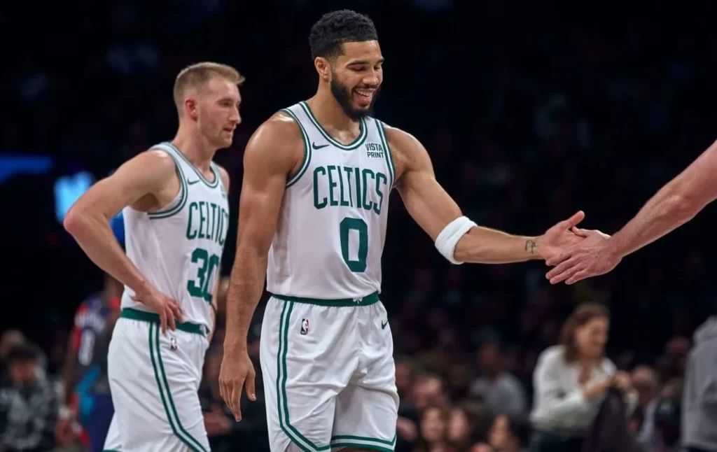 Teammates congratulating Jayson Tatum on-court after a spectacular play.