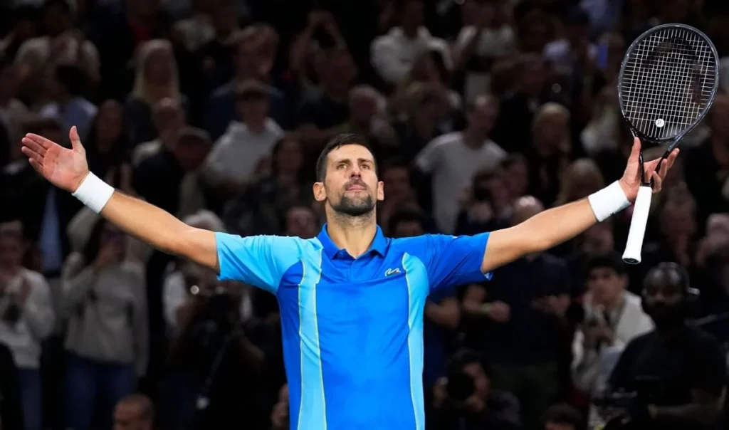 Novak Djokovic triumphantly raising his hands after a victorious match.