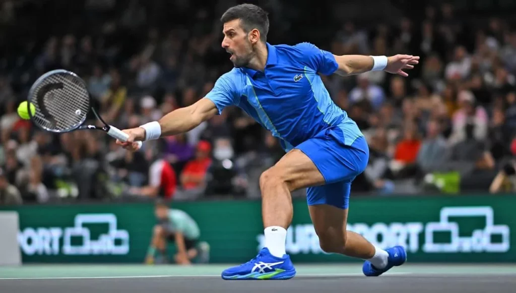 Tennis champion Novak Djokovic slides to hit a forehand shot.