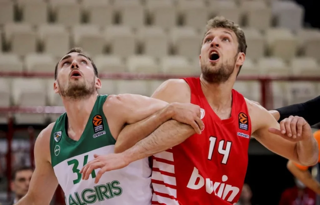 Intense physical battle under the rim between Olympiacos and Zalgiris athletes.