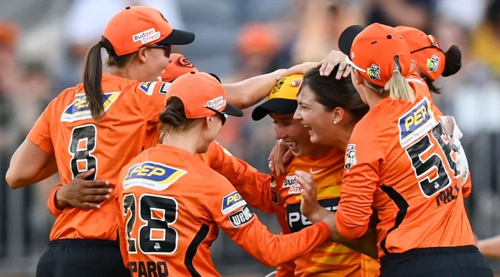 Elated Perth Scorchers Women players rejoicing on the sports field.