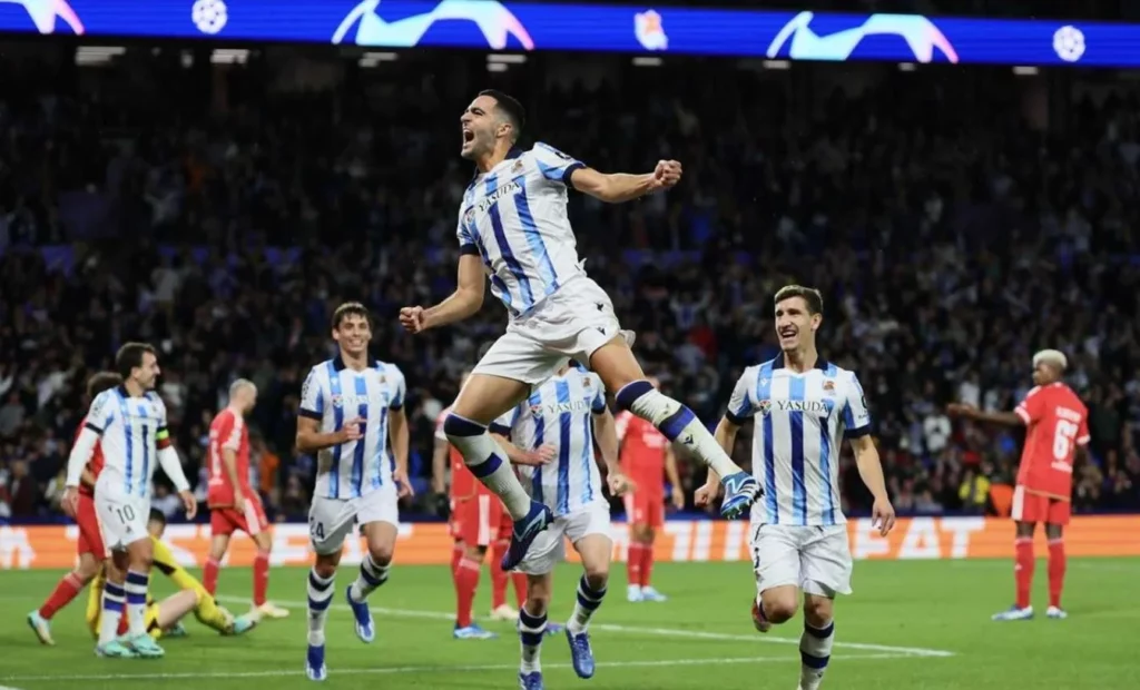 Real Sociedad players exultantly cheering following a successful goal.