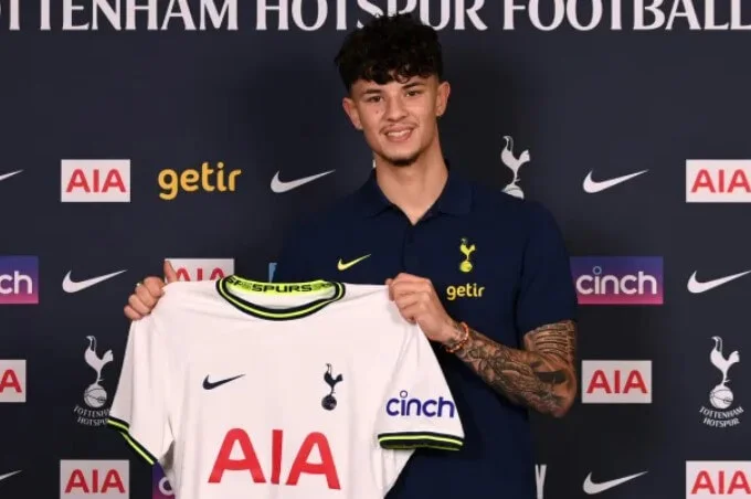 Jude Soonsup-Bell holding a Tottenham jersey at his contract signing ceremony.