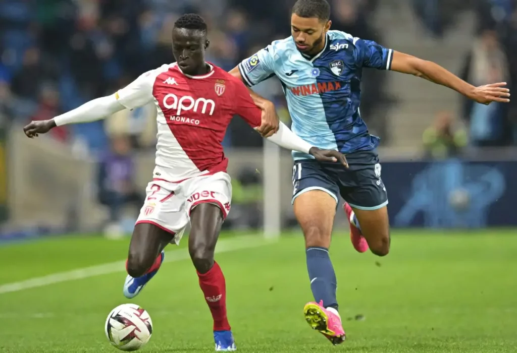 Monaco player charging forward with the ball in a Ligue 1 match.